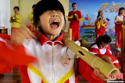 An Xingxing, 9, the youngest player in the team, practices percussion. It was the third bamboo tube that she has broken. Photo - Chinanews by Zhang Yuan 